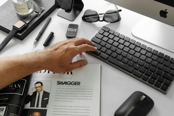 pexels-photo-3143791-3143791 A modern desktop setup featuring tech gadgets and a stylish magazine in an office setting.